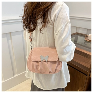 Pink pleated crossbody bag with silver butterfly buckle shown on a model's shoulder