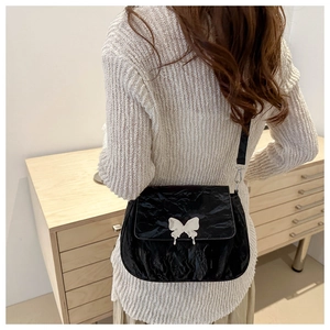 Close-up of the black pleated leather crossbody bag with a silver butterfly metal clasp