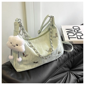 Detail of mint green tote bag featuring metal butterfly charms and silver chain strap