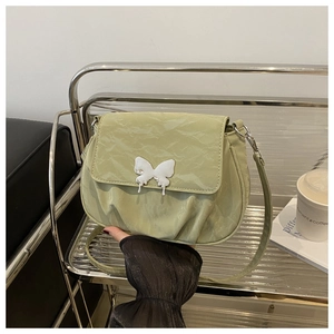 Detailed close-up of light green pleated shoulder bag featuring a silver butterfly buckle