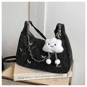Detail of black pleated shoulder bag with silver butterflies and plush cloud charm