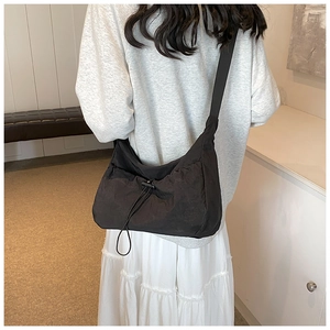Rear view of model wearing a minimalist black drawstring tote bag with nylon texture