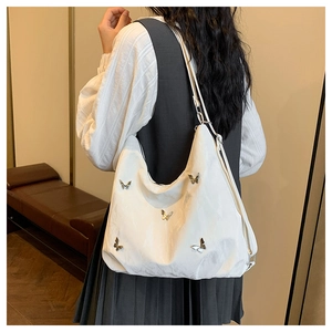 White hobo shoulder bag with silver butterfly charms and pleated texture on the strap