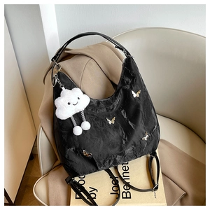 Detail of black hobo bag with silver butterfly charms and white plush cloud pendant