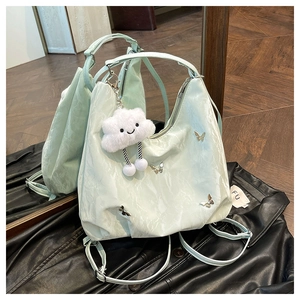 Mint green oversized hobo bag with metal butterfly charms on black leather jacket background
