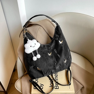 Black pleated hobo bag with butterfly details and cloud pendant on white leather seat