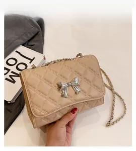 Detail of beige quilted flap bag with silver metal bow and chain strap texture