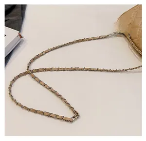 Detail of beige quilted bag strap featuring premium metal chain and leather weaving