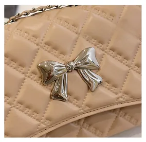 Close-up of beige quilted texture and silver bow buckle on the elegant chain shoulder bag