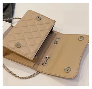 Detail view of the secure silver magnetic clasps on a quilted beige crossbody bag