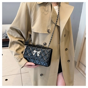 Close-up of black quilted crossbody bag with silver bow clasp and chain strap