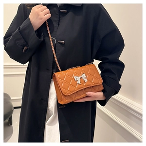 Chic brown quilted crossbody bag with silver bow detail and metal chain strap on model