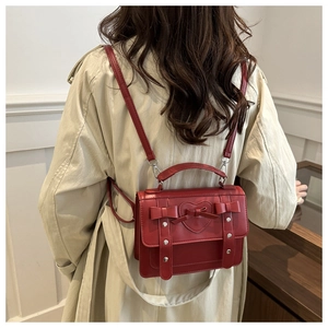 Detailed back view of a dark red structured bag with bows and heart relief on a trench coat