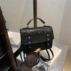 Chic black faux leather satchel bag with heart detail and decorative ribbons for women