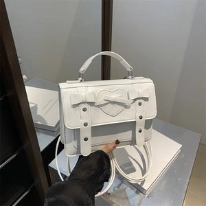 White multi-purpose satchel bag with heart stitching and bow details in a room setting