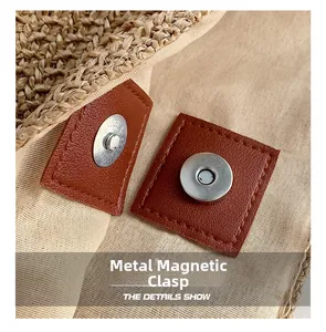 Detail view of the metal magnetic closure on the straw bag with leather reinforcement