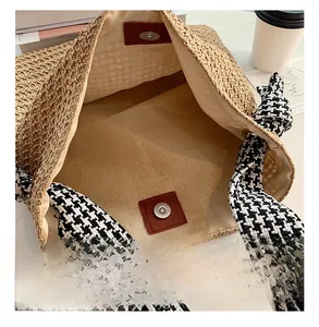 Detail view of woven straw tote bag featuring magnetic closure and houndstooth strap