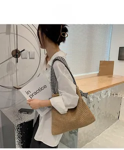 Detail of woven straw tote bag featuring stylish black and white houndstooth strap