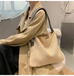 Detail of woven straw tote bag with a stylish black and white houndstooth shoulder strap