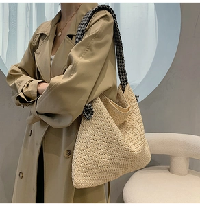Detail of woven straw tote bag featuring chic black and white houndstooth shoulder straps