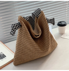 Close-up of woven straw handbag featuring elegant black and white houndstooth fabric trim