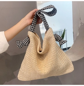 Detail der gewebten Strohtasche mit schickem Hahnentritt-Gurt und dekorativen Schleifen