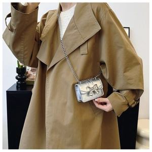Détail d'un mini sac bandoulière argenté avec nœud métallique et fine bandoulière