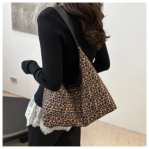 Gros plan du sac hobo léopard avec large bandoulière en cuir noir porté par le mannequin