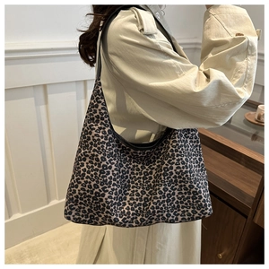 Detail showing leopard print tote bag on shoulder with black trim and canvas texture
