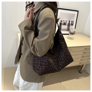 Détail d'un grand sac cabas à imprimé léopard avec une bandoulière noire sur modèle