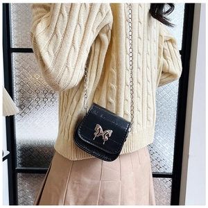 Detail of a mini black crossbody bag with silver butterfly chain and shiny leather finish