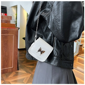 Detail of white crocodile texture mini bag featuring a silver butterfly chain strap