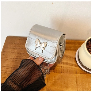 Gros plan détaillé du mini sac à chaîne argenté avec ornement papillon et texture brillante
