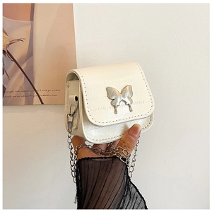 Macro view of white croc-effect mini bag featuring a silver butterfly chain link