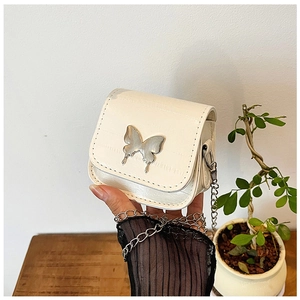 Détail d'un mini sac beige bandoulière avec chaîne papillon argentée et texture croco