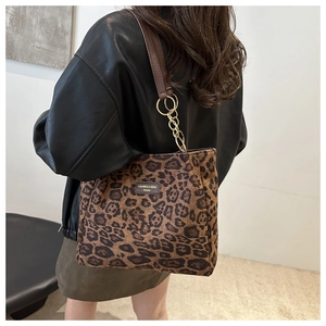 Detail of leopard print tote bag with leather strap and gold chain metal accents