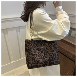 Close-up of leopard print tote bag with gold chain strap and leather brand tag
