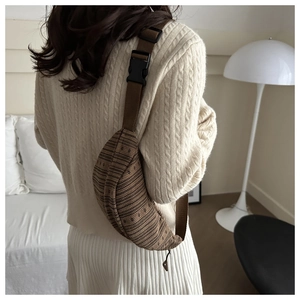 Detail van bruine corduroy crossbodytas met streepjespatroon en verstelbare schouderband