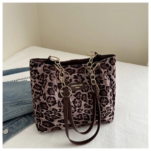 Detail of leopard print tote bag with golden metal chain and leather handle texture