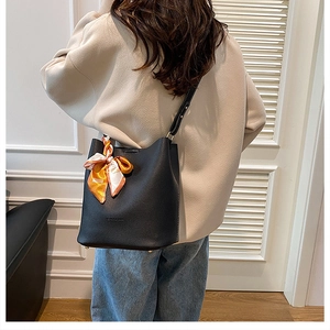Detail of black pebbled leather bucket bag with printed scarf on casual model