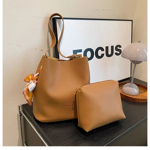 Detail of caramel lychee leather bucket bag with matching pouch and silk scarf handle
