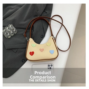 Detail of beige shoulder bag with colorful heart embroidery and dual straps next to a phone