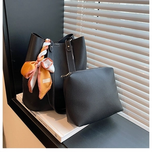 Detail of black lychee grain leather tote bag with stylish silk scarf and white stitching