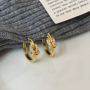 Detailed macro of gold-plated knot hoop earrings with pavé set white zirconias