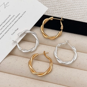 Twisted rope gold and silver hoop earrings set in a matte metallic minimalist design