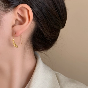 Elegant gold hoop earrings with wheat ear texture worn by a model in a white shirt