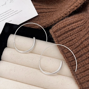 Macro detail of silver spiral earrings on beige velvet tray with autumn knit decor