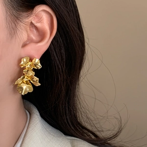 Elegant gold flower petal earrings with organic multi-layered design on a model's ear
