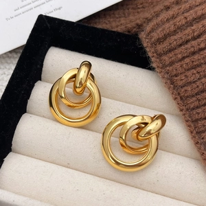 Detailed close-up of gold interlocking triple hoop earrings displayed in a beige jewelry box