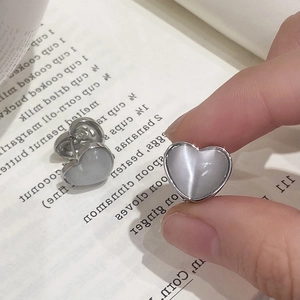 Elegant heart-shaped opal earrings with silver frames shown in a lifestyle setting